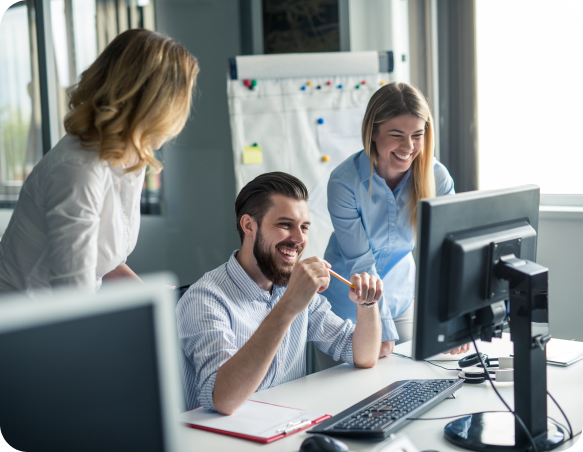 Team collaborating in a modern office, smiling and discussing work in front of a computer